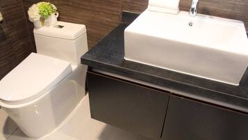 Un baño moderno con inodoro blanco, encimera negra y lavabo blanco.