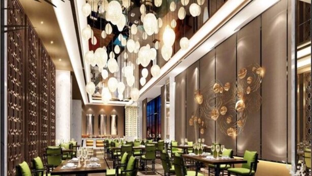 Un intérieur de restaurant moderne avec des chaises et des tables vertes, ainsi qu’un luminaire décoratif au plafond.