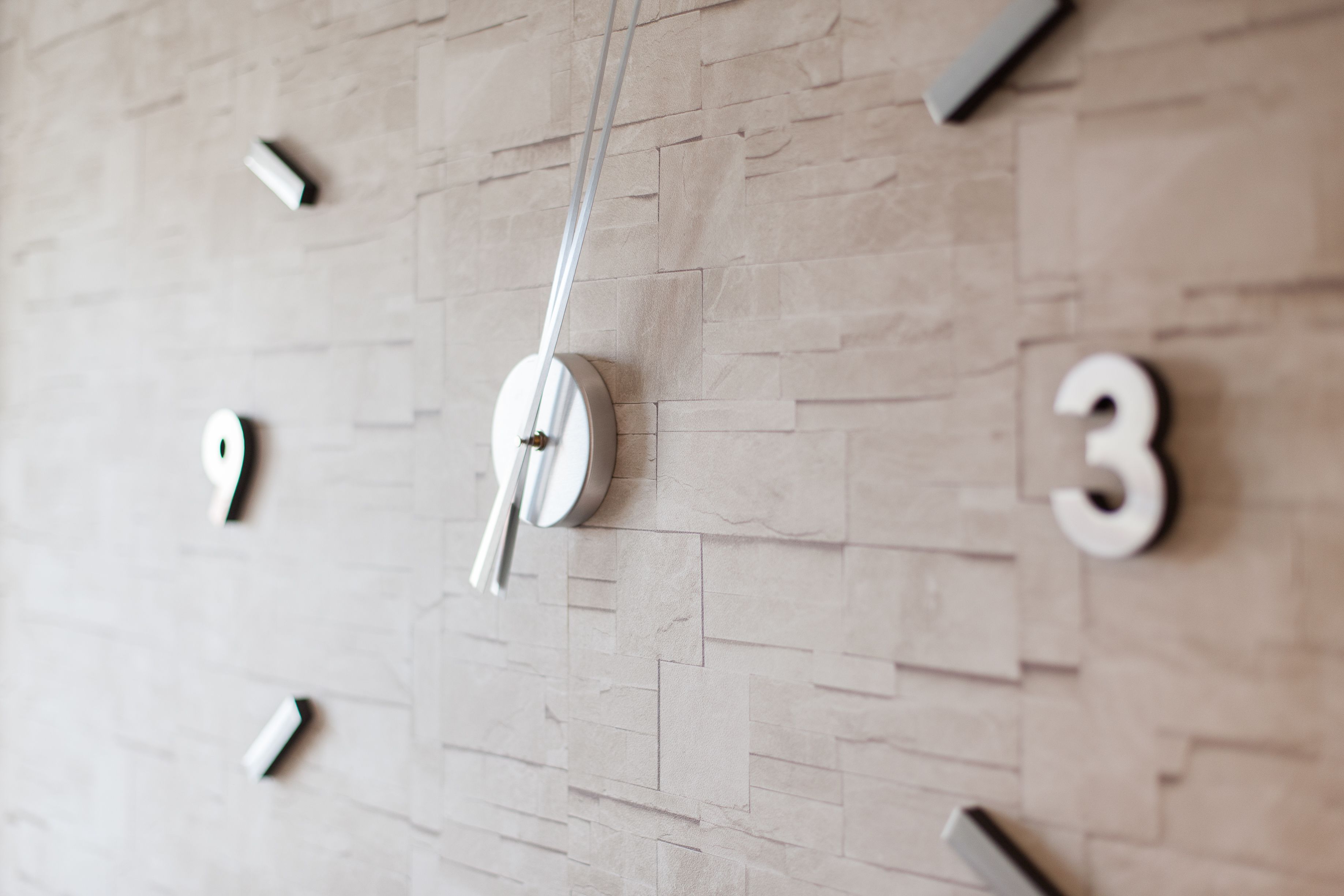 Eine Wanduhr mit minimalistischem Design, mit heller Holzstruktur und schlichten, modernen Ziffern.