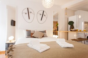 A modern hotel room with a large bed, a breakfast bar, and a kitchen area. - Moniz Studio Apartment - by LU Holidays (Lisbon)