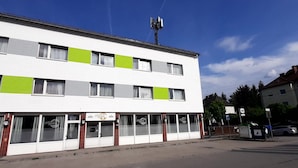 A two-story building with a white facade and green horizontal stripes. - Apartments CITY Stadion (Linz)