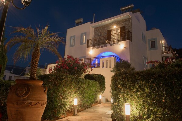 A two-story building with a balcony and a blue-lit archway at the entrance.