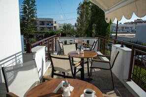 A terrace with outdoor seating, including tables and chairs, and a view of the surrounding buildings and greenery. - Moonlight Hotel (Hersonissos)