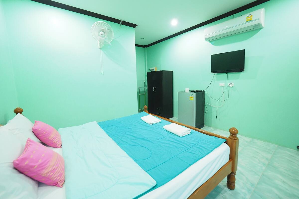 A room with a bed, a fan, an air conditioner, a TV, and a wardrobe.