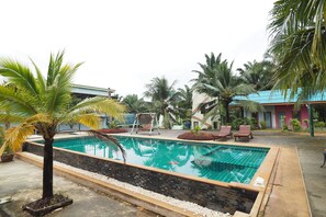 A swimming pool with a tiled edge, surrounded by palm trees and lounge chairs. - Sai Rung Resort (Krabi)