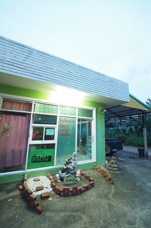 A building with a green facade, a covered entrance, and a small garden area with bricks and plants. - Sai Rung Resort (Krabi)