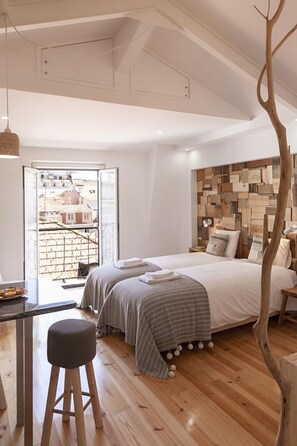 A modern bedroom with a large bed, a wooden headboard, and a view of the city through a glass door. - Bairro Studio Apartment - by LU Holidays (Lisbon)