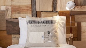 A pillow with a printed label reading "MANUFACTURE BRADLEY&CO" and a small envelope with a postmark. - Bairro Studio Apartment - by LU Holidays (Lisbon)