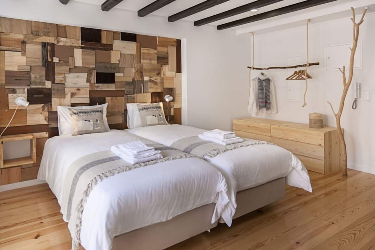 A bedroom with a wooden headboard, a wooden dresser, and a hanging coat rack.