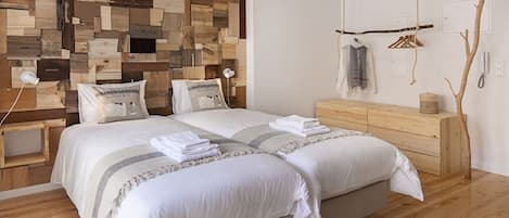 A bedroom with a wooden headboard, a wooden dresser, and a hanging coat rack.