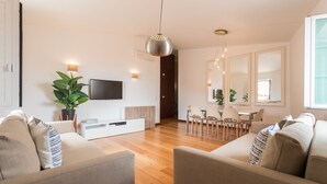 Ein modernes Wohnzimmer mit Sofa, Fernseher und Essbereich.