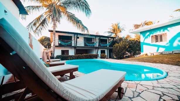 A poolside area with lounge chairs, a swimming pool, and a two-story building with balconies.