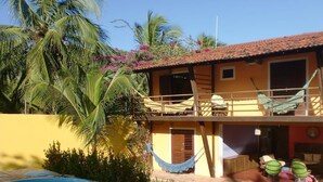 A two-story building with a balcony, a hammock, and a pool.