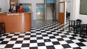 A reception area with a checkered floor, a reception desk, and a staircase leading to another floor. - Welcome Guest House (Patong)
