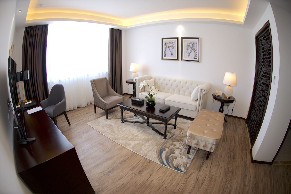Ein Hotelzimmer mit Sofa, Sessel, Couchtisch und Schreibtisch mit Lampe.