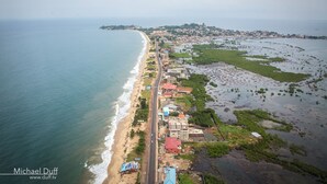 An aerial view of a coastal town with a beach, buildings, and a road.