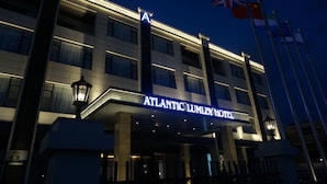 The exterior of the Atlantic Lumley Hotel with a prominent 'A' sign, multiple flags, and a well-lit facade. - Atlantic Lumley Hotel (Freetown)