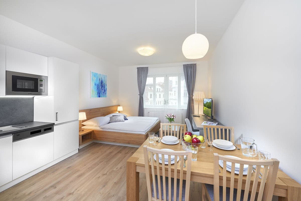 Een compacte hotelkamer met een kitchenette, een bed, een eethoek en een televisie.