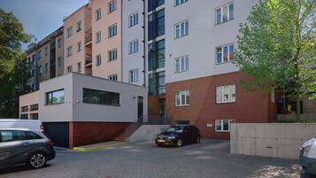 Un edificio residencial de varios pisos con un diseño moderno, que combina fachadas de ladrillo y vidrio, y un estacionamiento con automóviles.