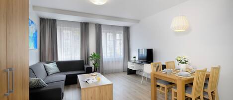 Een moderne woonkamer met een bank, salontafel, eettafel en stoelen.
