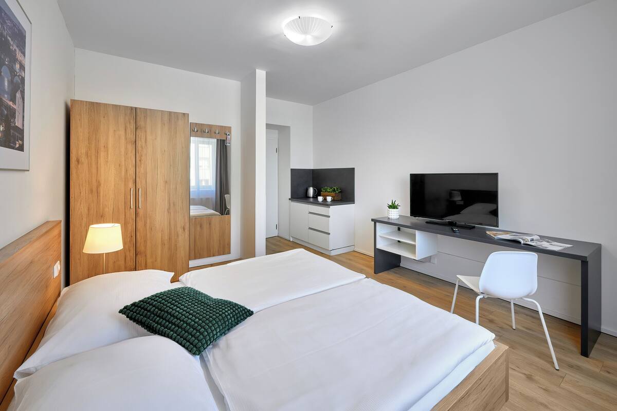 Een moderne hotelkamer met een groot bed, een bureau met een televisie, een stoel en een kledingkast.
