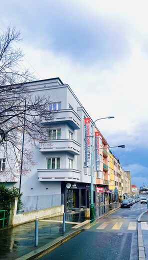 Un bâtiment moderne à la façade sobre et aux grandes fenêtres, avec des enseignes indiquant « Downtown Suites » et « Angel Hotel ».