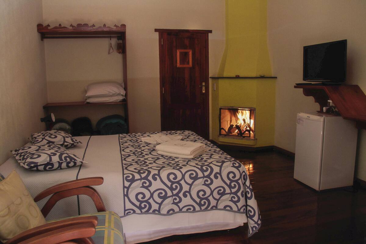 Une chambre à coucher comprenant un lit, une armoire en bois, un téléviseur et un petit réfrigérateur blanc.