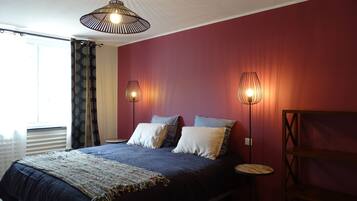 Une chambre à coucher avec un lit, deux lampes de chevet, une fenêtre avec des rideaux et un luminaire au plafond.