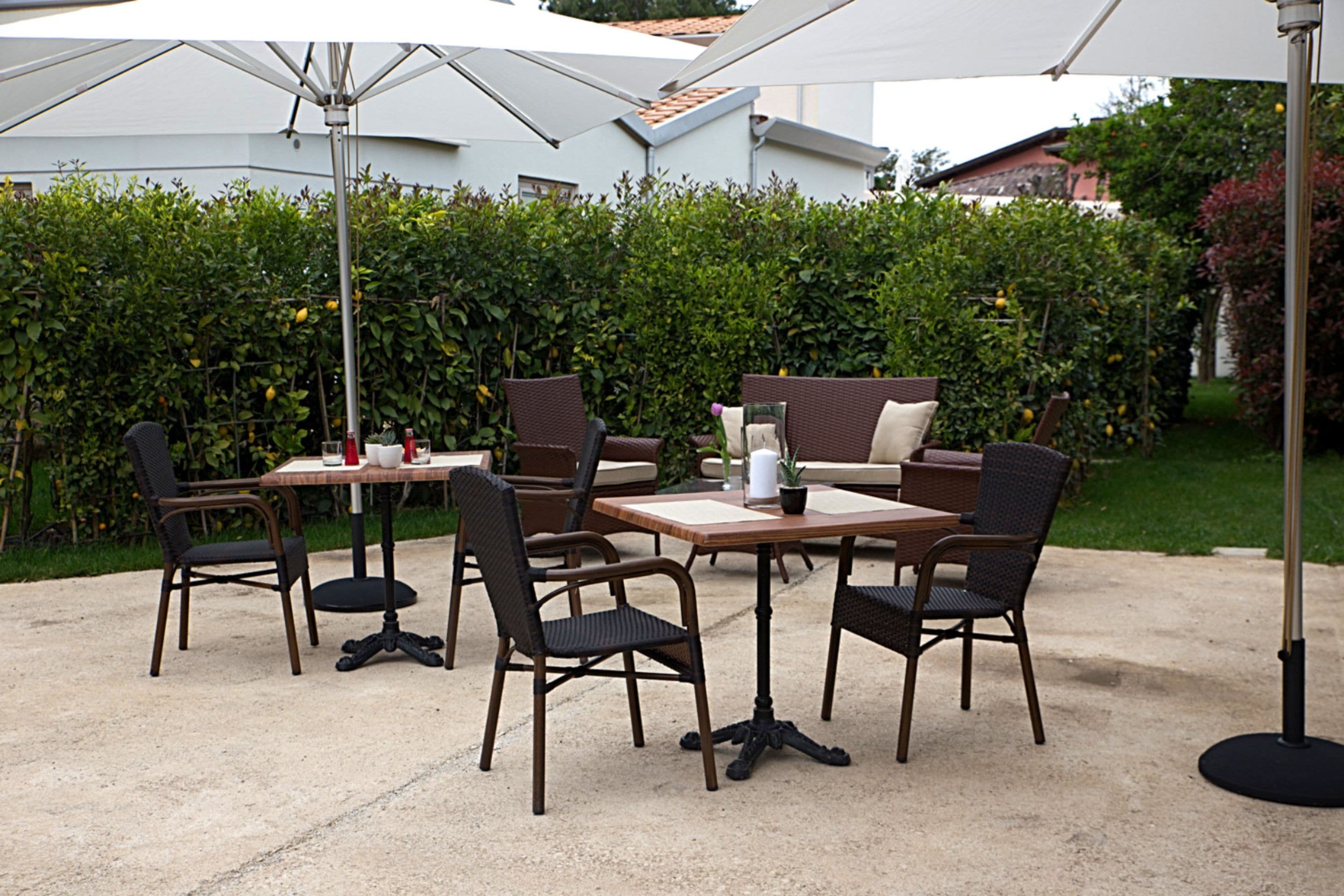 An outdoor patio with a table and chairs, a sofa, and umbrellas.