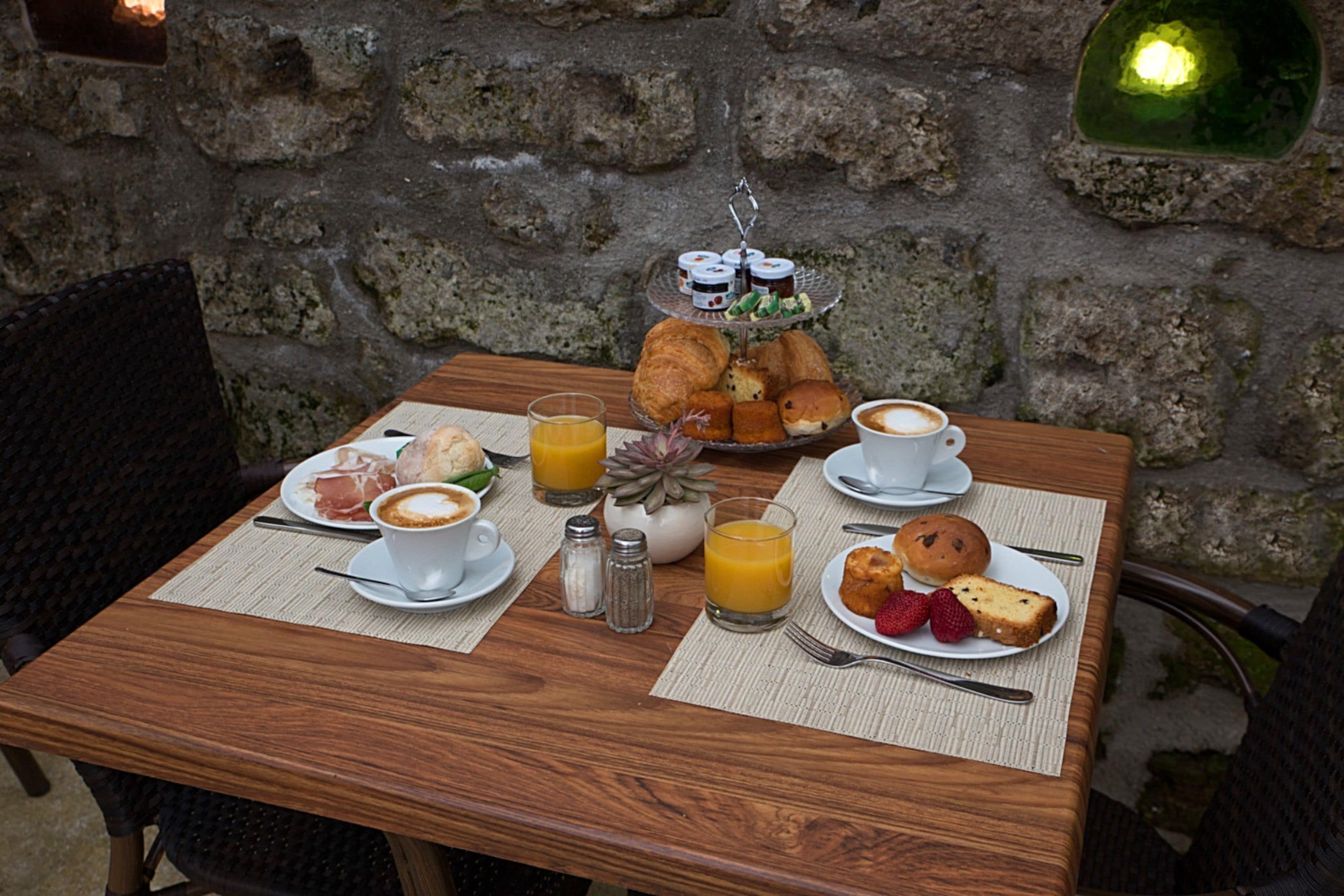 A breakfast table with croissants, pastries, coffee, and orange juice.