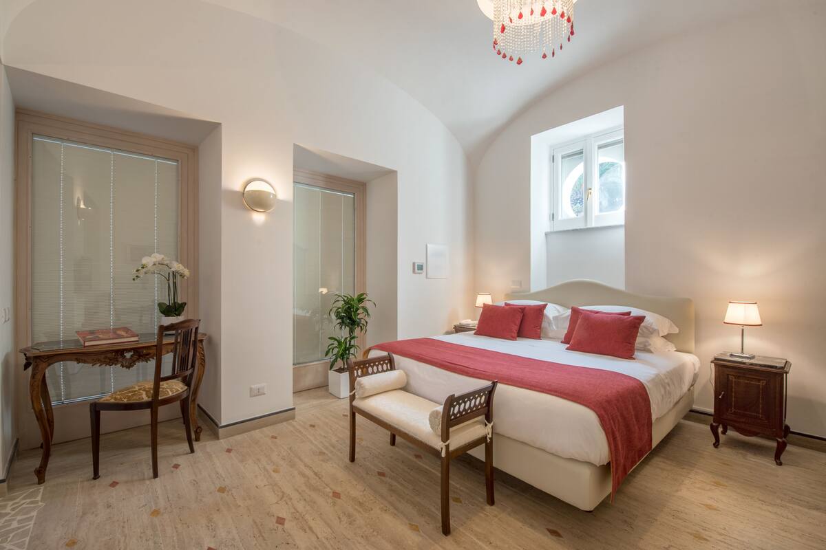 Un dormitorio con cama, mesitas de noche, un escritorio y sillas.
