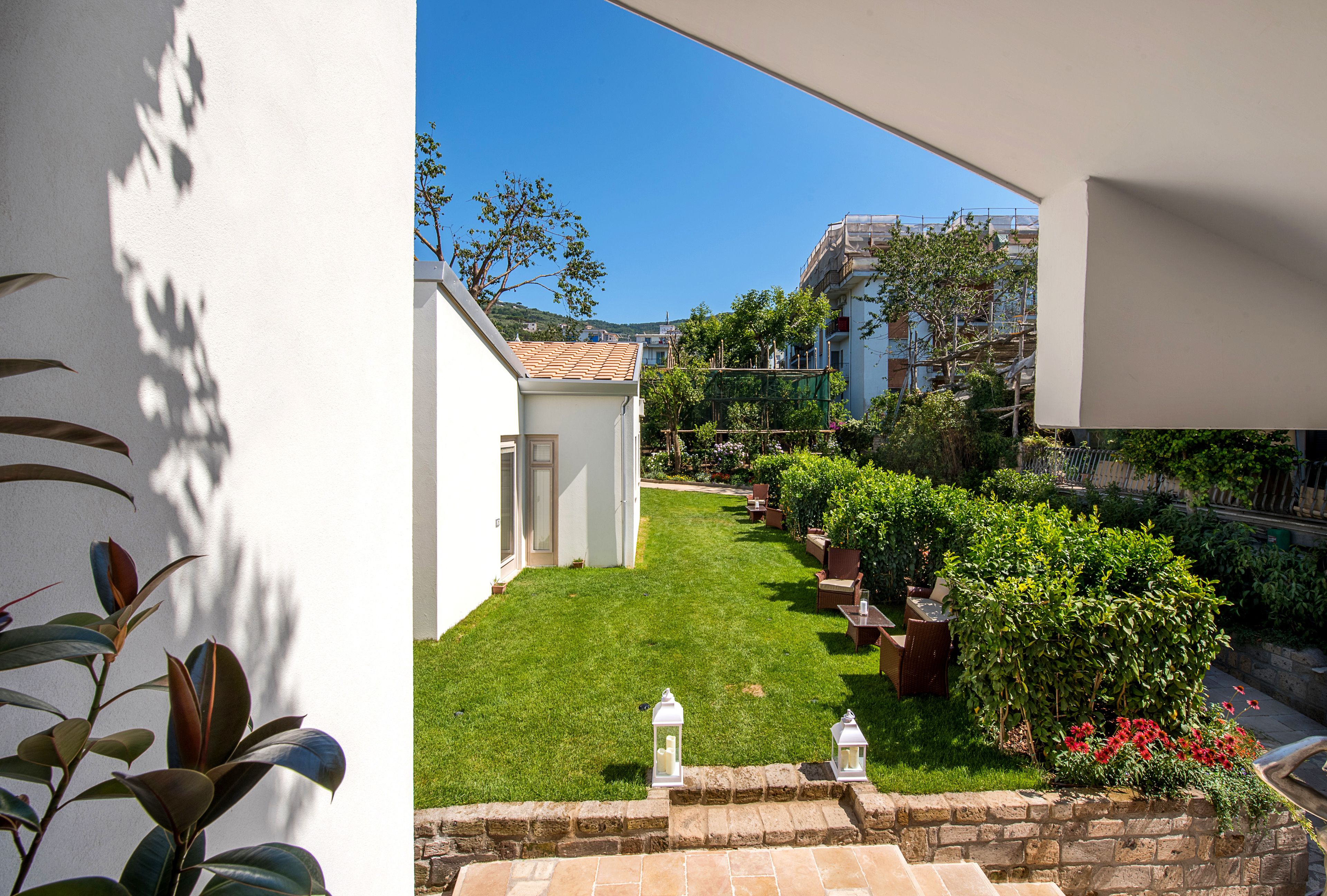 Un jardin bien entretenu, avec une pelouse, des plantes en pot et un mur de pierres.