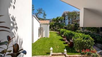 Un jardin bien entretenu, avec une pelouse, des plantes en pot et un mur de pierres.