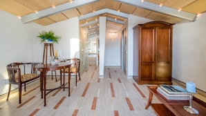Un pasillo espacioso con suelo de madera, un comedor con mesa y sillas, y un armario de madera.