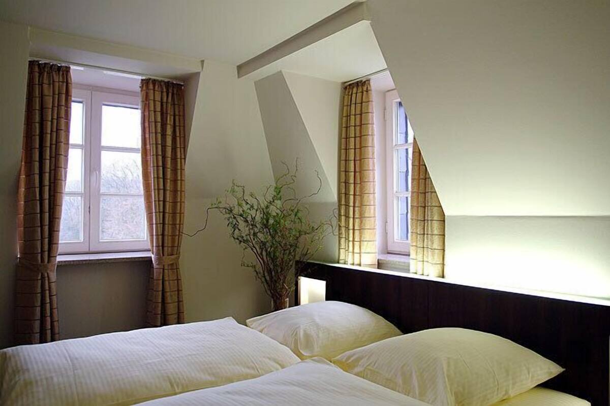 A bedroom with a bed, curtains, and a window.