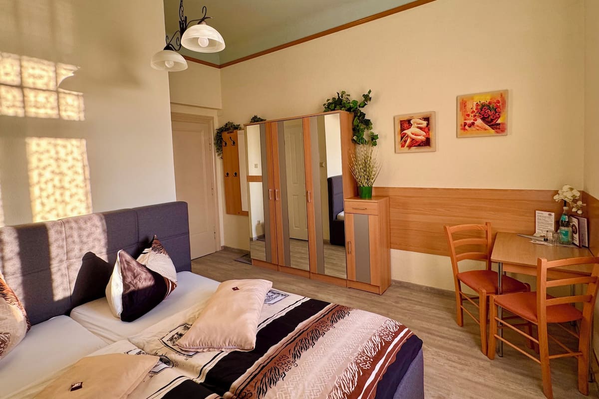A cozy room with a sofa, a dining table with chairs, a mirror, and artwork on the walls.