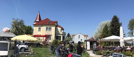 A sunny outdoor market with bicycles, a white building with a red roof, and a signboard.