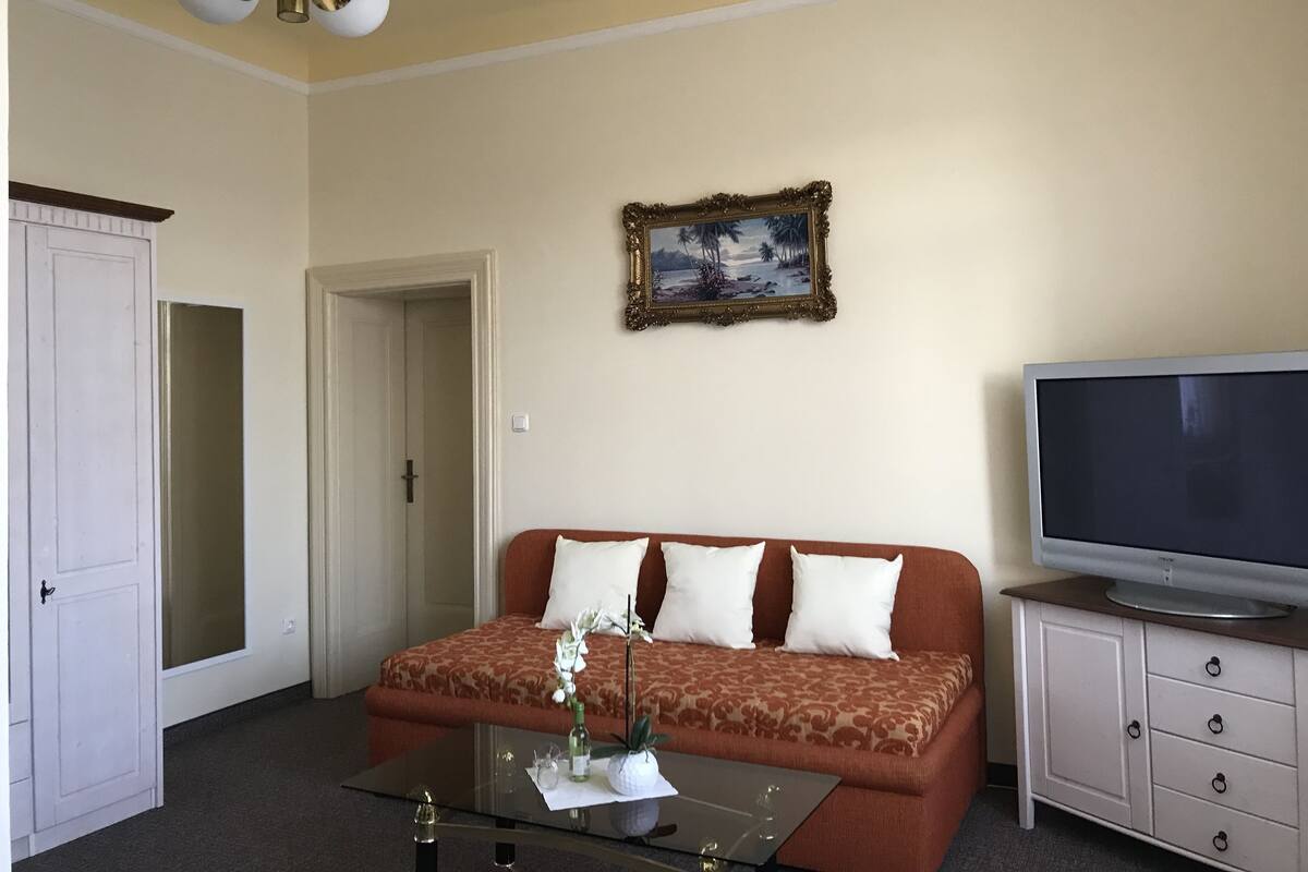 A living room with a sofa, a television, a cabinet, and a painting on the wall.