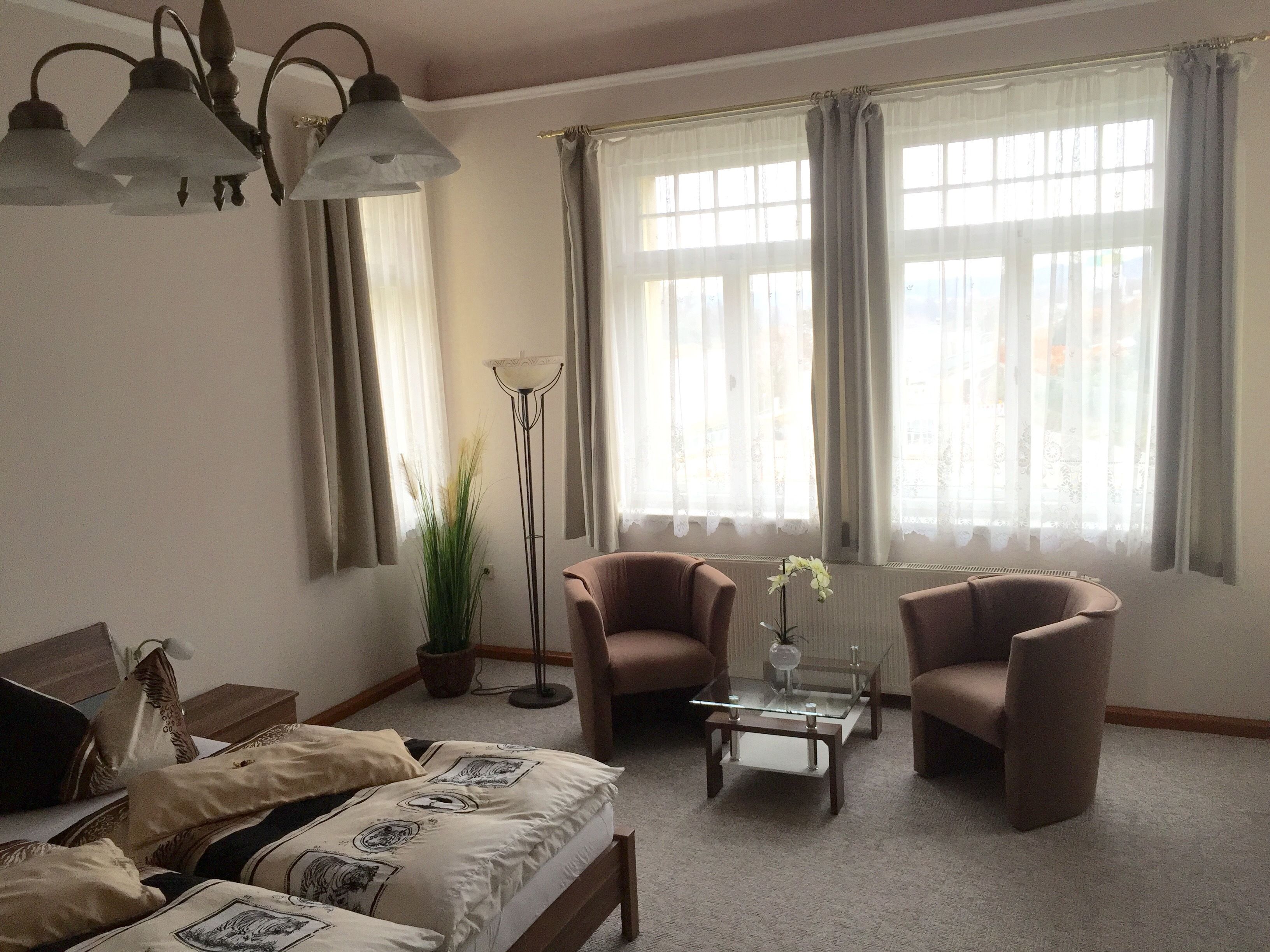Un salon confortable avec un lit, deux fauteuils, une table basse et une lampe sur pied.