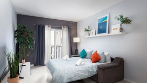 A modern bedroom with a bed, a sofa, a potted plant, and a window with curtains. - Modern 3 Bedroom 3 Bathroom Near Balluta Bay Sliema (St. Julian's)