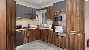 A modern kitchen with wooden cabinets, stainless steel appliances, and a tiled backsplash. - Modern 3 Bedroom 3 Bathroom Near Balluta Bay Sliema (St. Julian's)