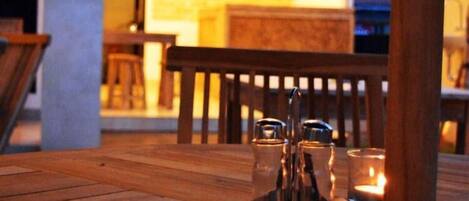 A wooden table with salt and pepper shakers, a candle, and a flower.
