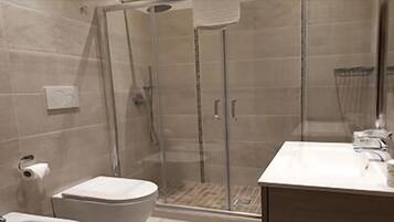 Un baño con ducha de vidrio, inodoro y lavamanos con espejo.