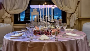 A table set for a meal with candles, glasses, and plates, overlooking a scenic view. - Villa Degli Angeli (Castel Gandolfo)