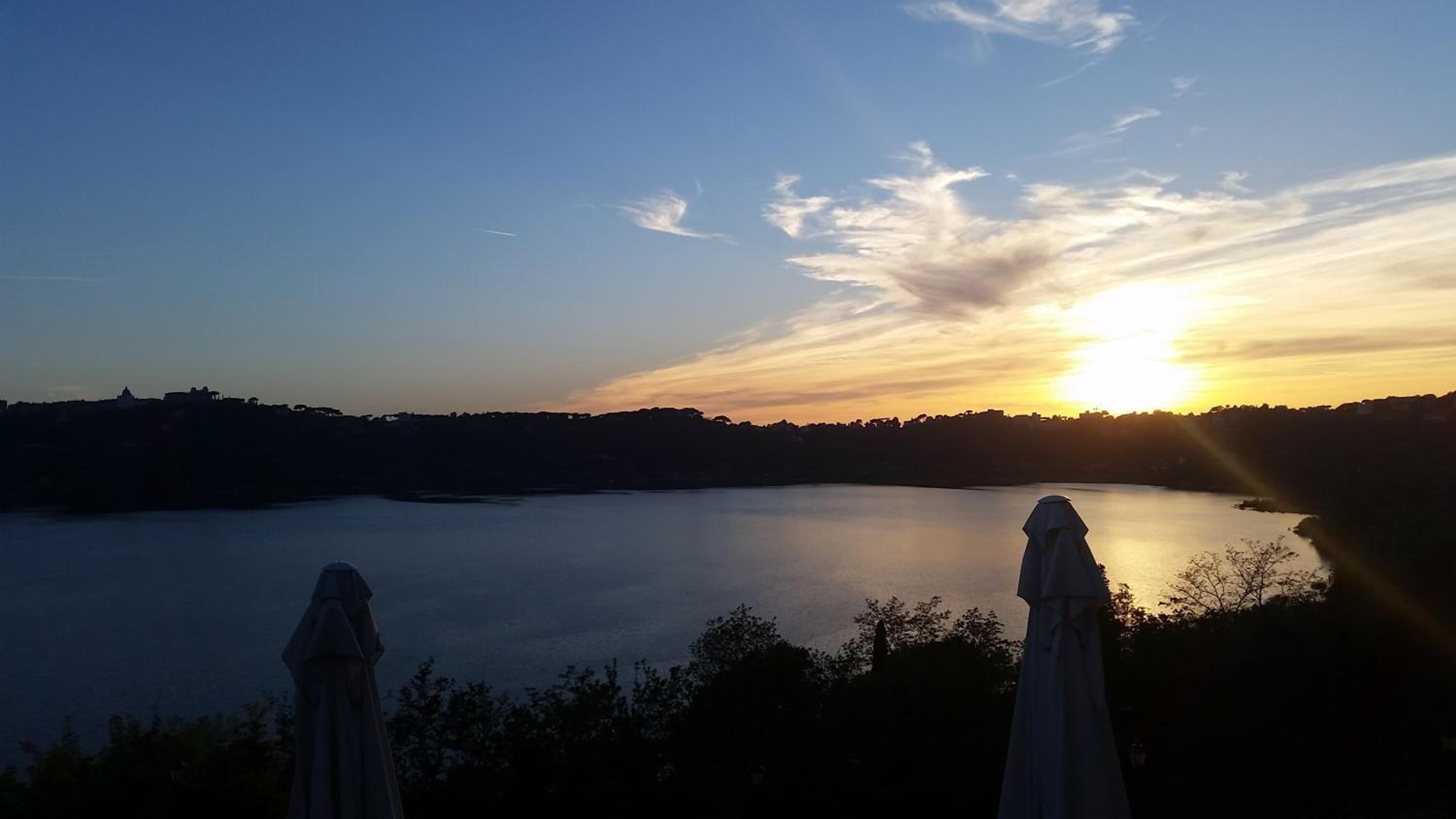 Un coucher de soleil paisible sur un lac calme, avec deux statues au premier plan.
