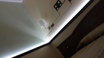 Un coin de pièce avec un lit, une lampe fixée au mur et une prise de courant.