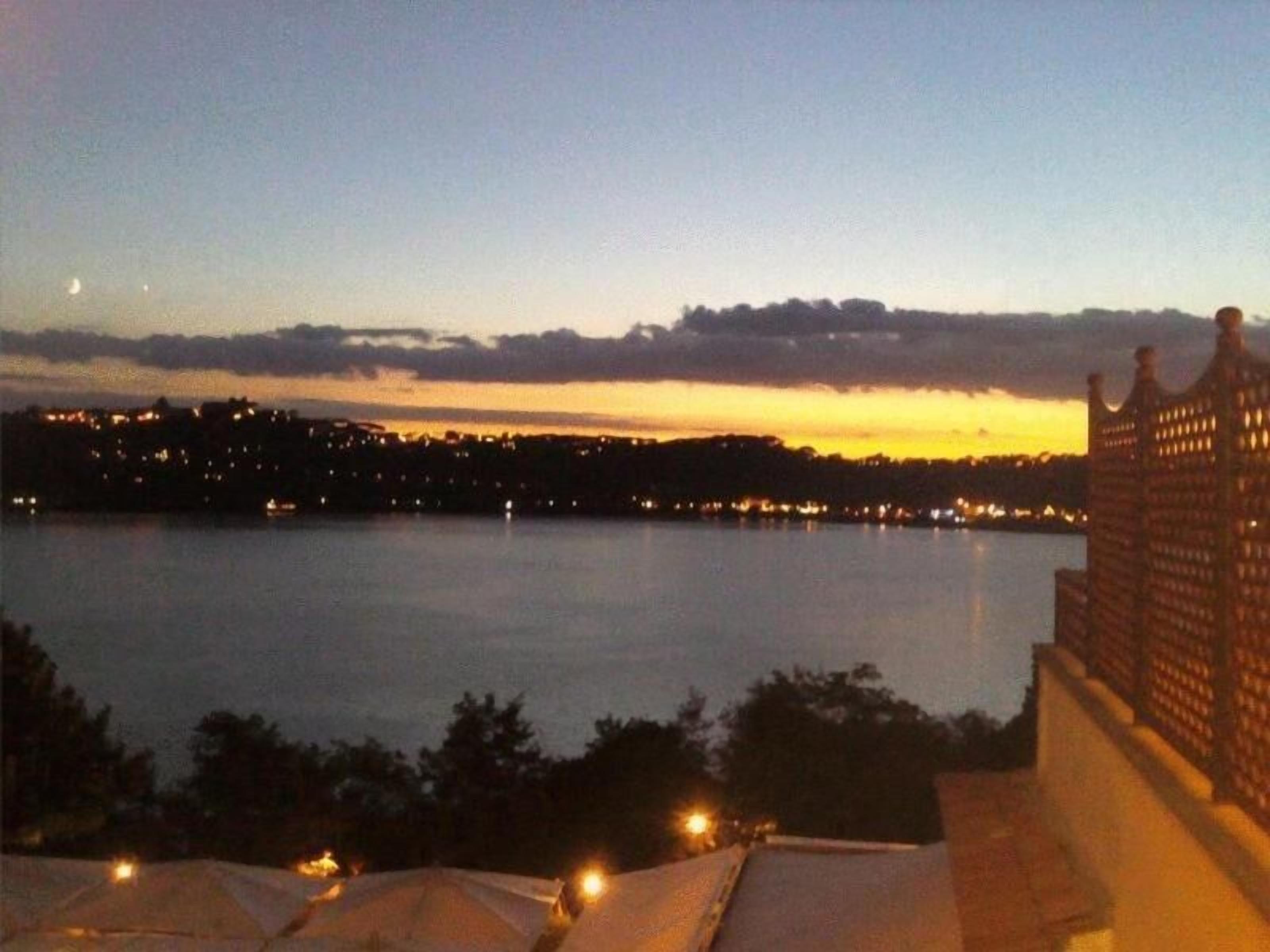 A nighttime view of a waterfront with a city skyline in the background.