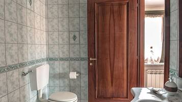Uma casa de banho com sanita, bidé e lavatório.