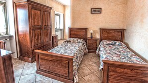 Un dormitorio con dos camas de madera, una mesita de noche, un aparador y una ventana.