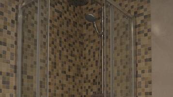 A glass-enclosed shower with a tiled mosaic wall.